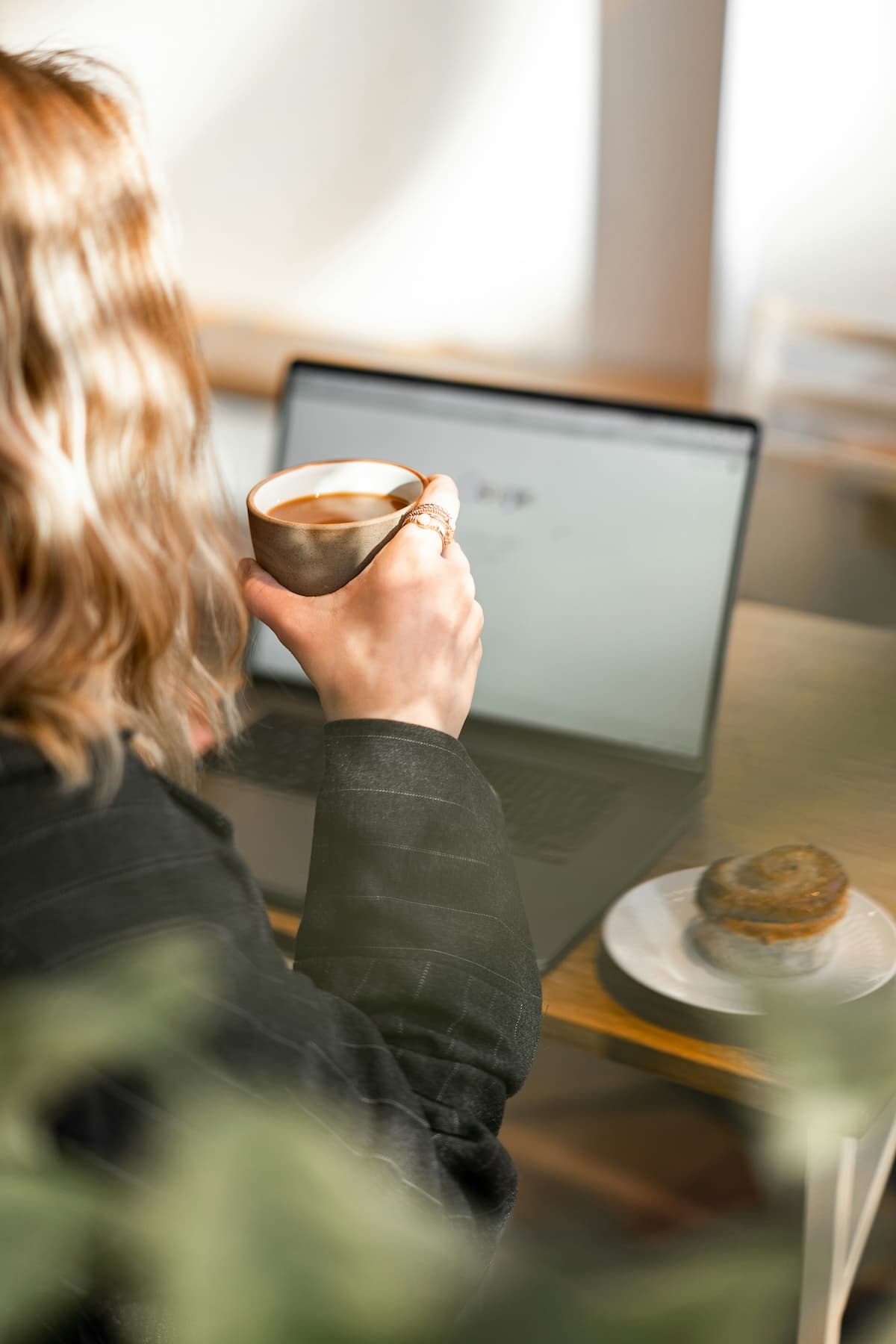Business owner reviewing her laptop while enjoying coffee