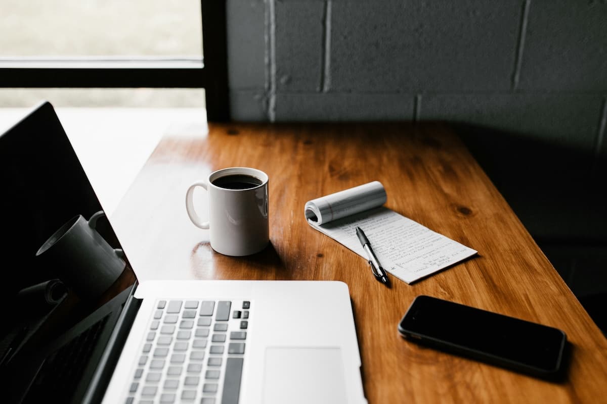Coffee, notebook, and laptop on a desk